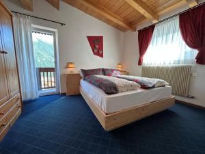 a bedroom with a bed and a large window at Hotel Vigo in Vigo di Fassa