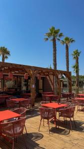 a patio with tables and chairs and palm trees at Camping du Pas Del Fang in Sainte-Marie-la-Mer