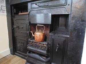an old black stove with a copper pot in it at Oswin Cottge in Alnwick