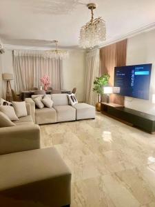 a living room with couches and a large screen tv at Elegant apartment in New cairo