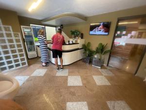 a man and a woman standing at a counter at Pousada Maré Alta em Pajuçara in Maceió