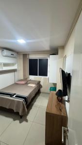 a bedroom with a bed and a desk and a television at Quarto em Ap no Renascença in São Luís