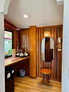 ein Raum mit Holzwänden und einem Spiegel und einem Hocker in der Unterkunft Pen's Bungalow Koh Phangan in Thong Nai Pan Yai