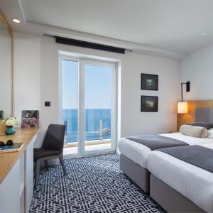 a hotel room with a bed and a desk and a window at Royal Neptun Hotel in Dubrovnik
