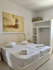 a white bedroom with two beds with towels on them at Aegeo Inn in Antiparos