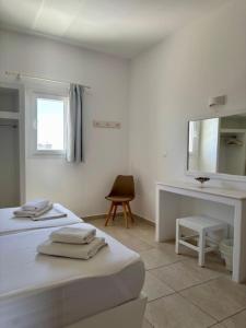 a white room with two beds and a mirror at Aegeo Inn in Antiparos