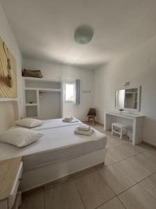 a white bedroom with a large bed and a desk at Aegeo Inn in Antiparos