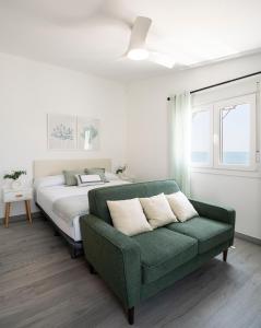 sypialnia z łóżkiem i zieloną kanapą w obiekcie Apartamentos Marina Playa en 1º línea junto al mar w mieście Rincón de la Victoria
