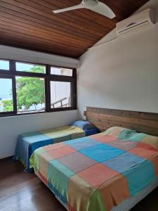 zwei Betten in einem Zimmer mit zwei Fenstern in der Unterkunft Casa na Barra do Una, à beira do Rio Una e frente a Praia in São Sebastião