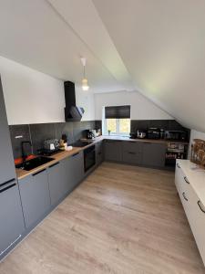 a large kitchen with gray cabinets and a wooden floor at New Exclusive 5 bedroom house for 8 persons - 155m2 in Marslev