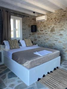 a large bed in a room with a stone wall at Darsi suites Kythnos in Kithnos