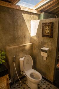 a bathroom with a toilet in a room at Wisnu Lumbung Uluwatu in Uluwatu