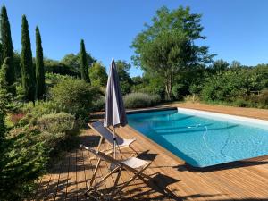 an umbrella and chairs next to a swimming pool at Le séchoir de Valadon in Aillas +34 photos