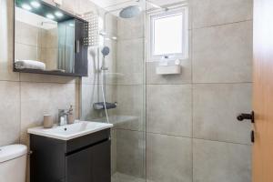 a bathroom with a shower and a sink and a mirror at Stylish 2BR Apartment with Rooftop Pool in Mackenzie in Larnaca
