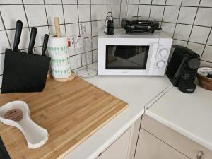 a white microwave sitting on a kitchen counter at Stylish 2BR Apartment with Rooftop Pool in Mackenzie in Larnaca