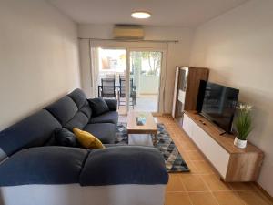 a living room with a blue couch and a television at Cosy Apartment in a Secured Compound of PlayaSol with Large Pools in Vinaròs