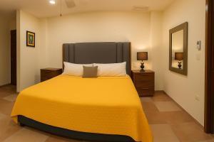 ein Schlafzimmer mit einem gelben Bett mit einem großen Kopfteil in der Unterkunft Ave Fénix Cozumel in Cozumel