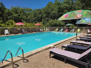 a swimming pool with lounge chairs and umbrellas at Kamea Club La Gironie in Turenne
