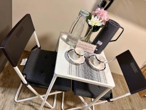 a white table with two chairs and a vase with flowers at South Breeze Stay Near Nuvali, Enchanted kingdom, Tagaytay in Silang