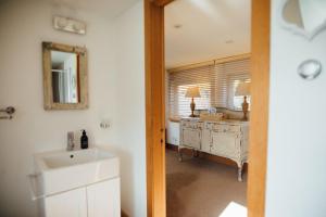 a bathroom with a sink and a desk with a mirror at Shell Cottage B&B in Toscaig