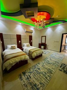 a hotel room with two beds and a chandelier at فوج فيو للفلل والشقق الفندقية in Al Namas +29 photos