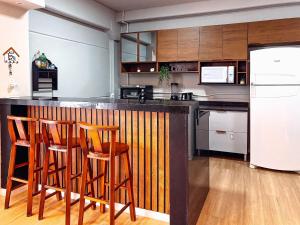 a kitchen with wooden bar stools and a white refrigerator at Casa espaçosa com 3 quartos | Até 11 pessoas in Limeiro