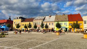 a group of buildings in a square with people walking at Dům Slunce in Nové Město pod Smrkem