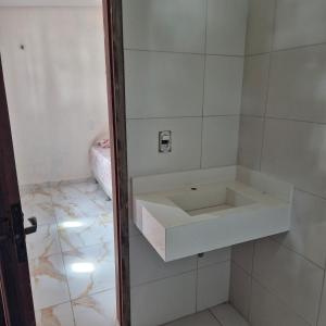 ein weißes Waschbecken in einem weiß gefliesten Bad in der Unterkunft Chácara Corujá in Juazeiro do Norte