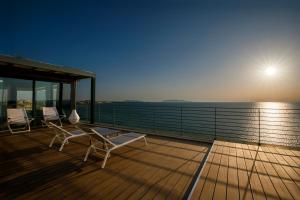 two chairs and a table on a deck with the ocean at Hotel Punta Tipa in Trapani