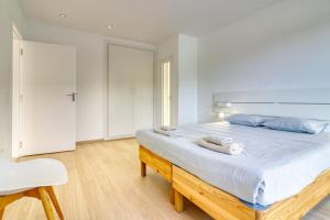 een witte slaapkamer met een groot bed met blauwe kussens bij Nice Home Costa Adeje in Adeje +28 foto's