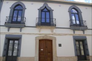 a white building with a wooden door and windows at Sueños del Geoparque in Logrosán