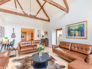 a living room with leather furniture and a table at Haybale Barn in Chatton