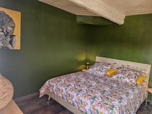 a bedroom with a bed with a green wall at Le petit Vincent, Studio élégant, central avec parking privé in Saint-Rémy-de-Provence
