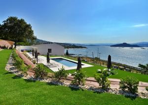 a garden with umbrellas and a swimming pool next to the water at GALIHOST - RD Hotel Apartamento in Raxo