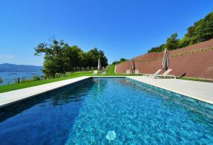 a swimming pool with blue water and umbrellas at GALIHOST - RD Hotel Apartamento con piscina climatizada in Raxó