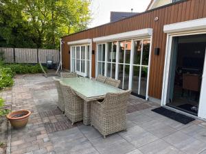 a patio with a table and wicker chairs at Maison Lelystad in Ons Belang