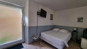 a bedroom with a bed and a television on the wall at Léa rdc centre-ville rénové concon cosy parking 36m2 in Charleville-Mézières