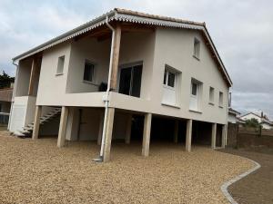 a white house with wooden poles around it at Maison pilotis 12 pers 50m mer in Les Moutiers