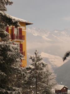 a yellow building with snow covered trees and mountains at Hotel Splendide in Champex