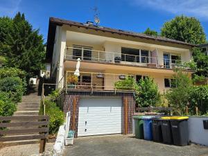 a house with a garage and two trash cans at Marburg Apartment feuriger Felix mit Kamin und Garten in ruhiger Waldrandlage in Marburg an der Lahn