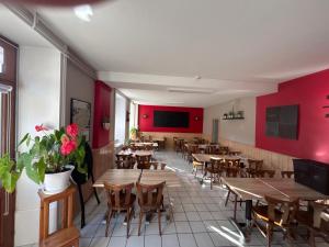 a restaurant with wooden tables and chairs and red walls at Lods Hotel de France in Lods