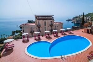 a large swimming pool with chairs and umbrellas in front of a building at Hotel Isola Bella in Taormina