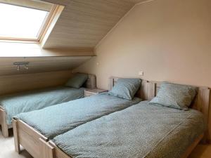 two beds in a room with a window at La pause Pom' de Pain appartement in Rochehaut