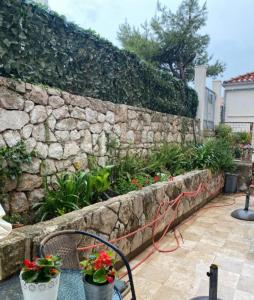 a stone wall with two potted plants and a bench at Daniele Garden in Dubrovnik