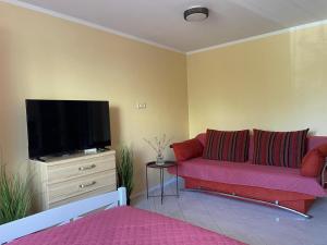 een woonkamer met een rode bank en een flatscreen-tv bij Elena in Ventspils