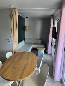 a dining room with a wooden table and white chairs at Mobil home 6 personnes à 400m de la mer in Argelès-sur-Mer +4 photos