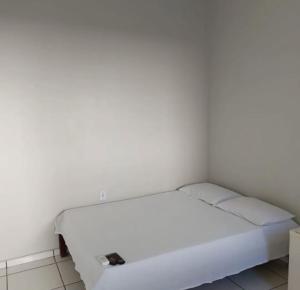 a white bed in a room with a white wall at Pousada Itororó in Bom Jesus da Lapa