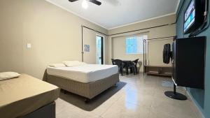 a bedroom with two beds and a flat screen tv at Suíte 04 • Praia das Pitangueiras in Guarujá