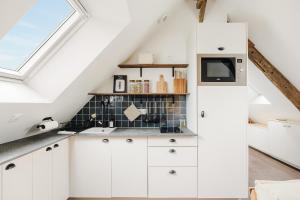 ポントルソンにあるLa Mer - Appartement calme et douillet à 5km du Mont St Miche - Wifi - Netflixの白いキャビネットと窓のあるキッチン