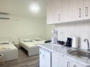 a white kitchen with a sink and two beds at TIKI Apartments in Gevgelija